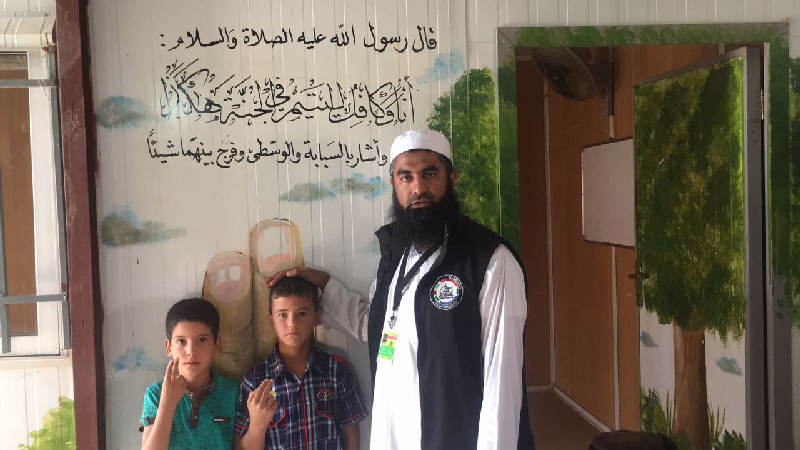Al-Imdaad Foundation’s Moulana Mohamed Motala together with two orphans  in front of a Hadith exalting the status of those who care for orphans